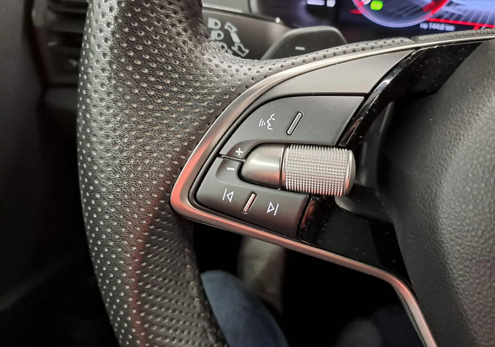 Gros plan sur les commandes multifonctions en métal et cuir perforé du volant du Skoda Karoq gris graphite 2025.
