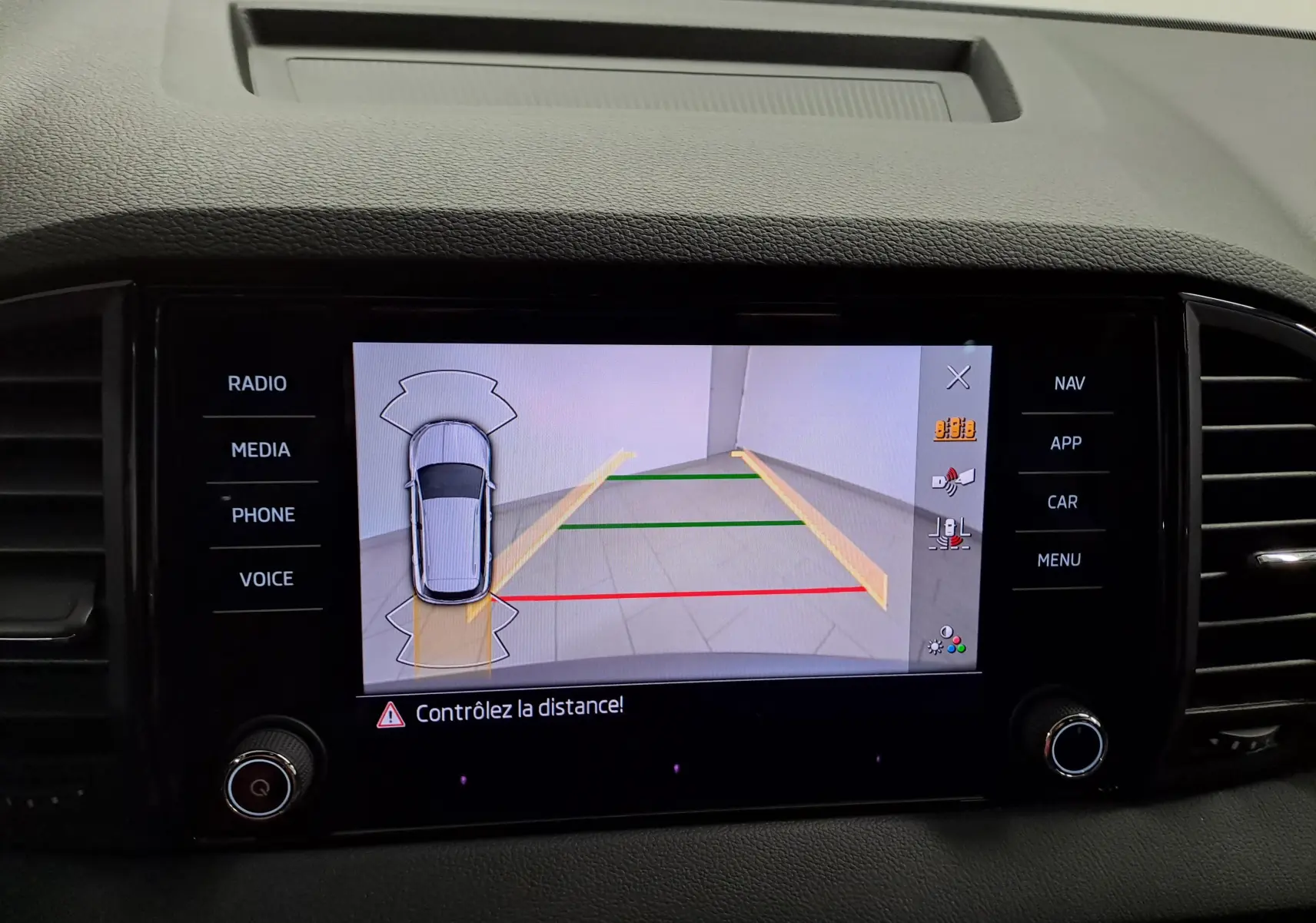 Écran central de la Skoda Karoq gris graphite montrant la caméra de recul avec lignes de guidage colorées.
