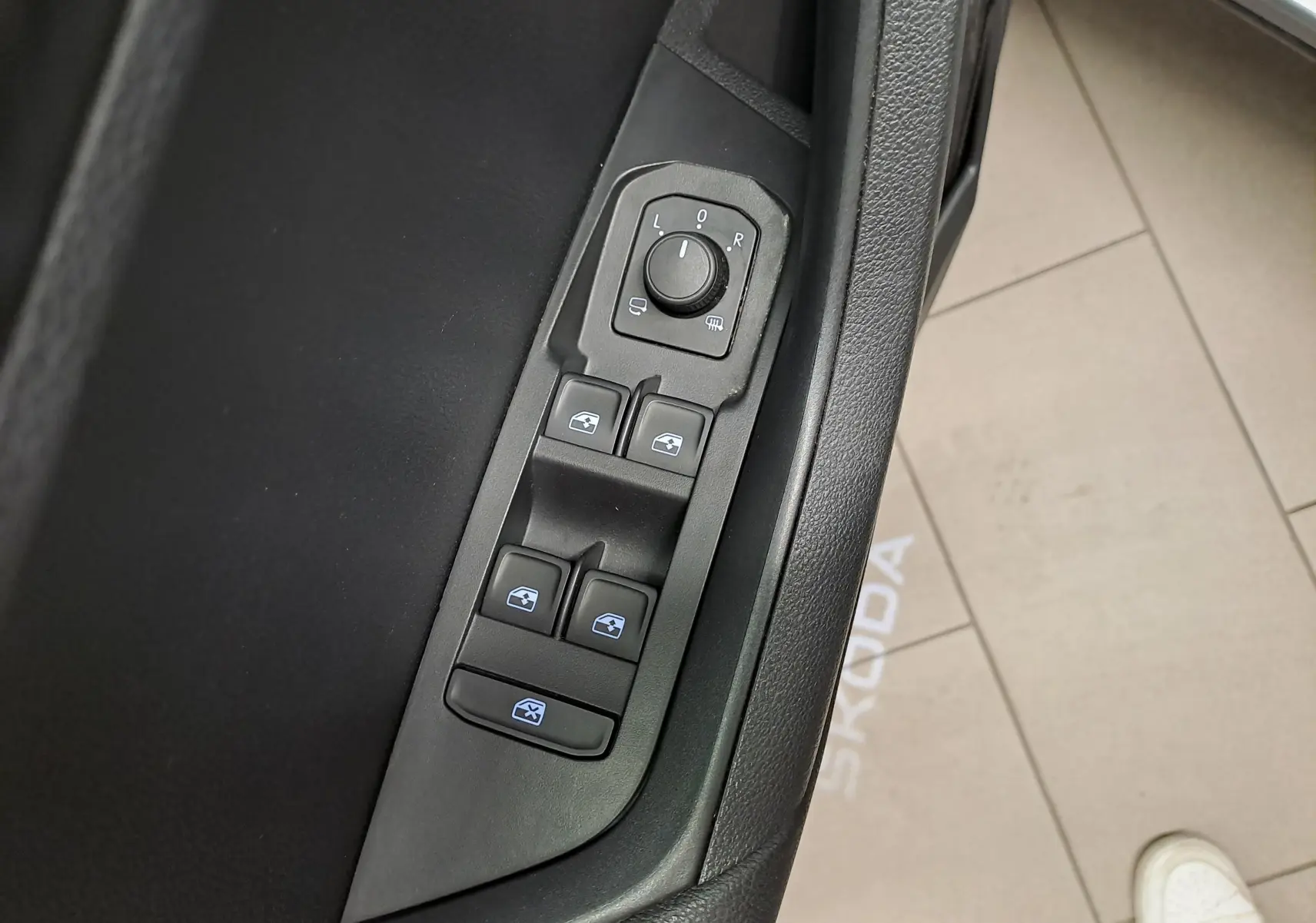 Détail des commandes des vitres et rétroviseurs côté conducteur d’un Skoda Karoq gris graphite, intérieur noir.