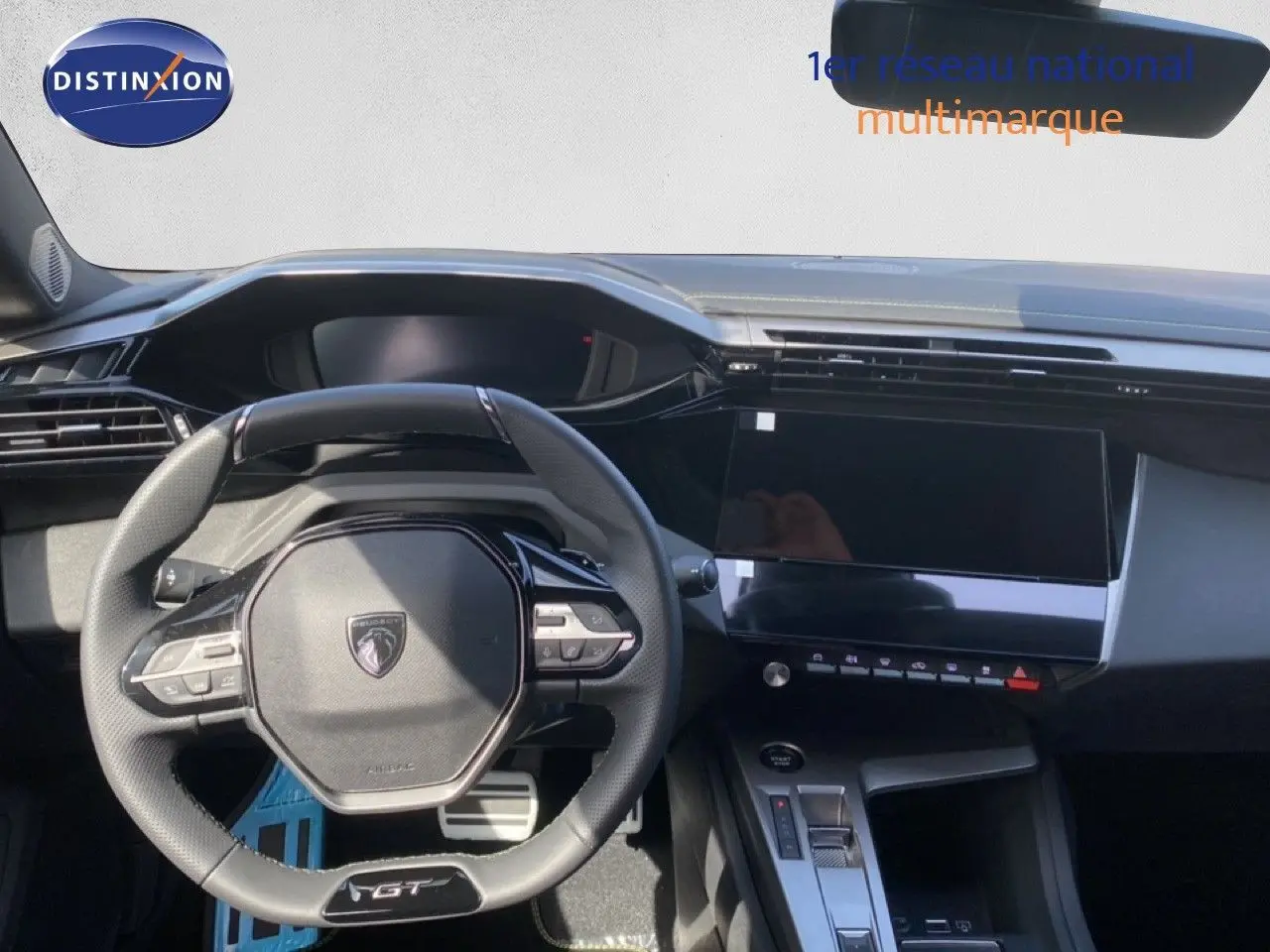 Vue intérieure centrée sur le volant GT et le tableau de bord moderne de la Peugeot 308 Hybrid blanche 2026.