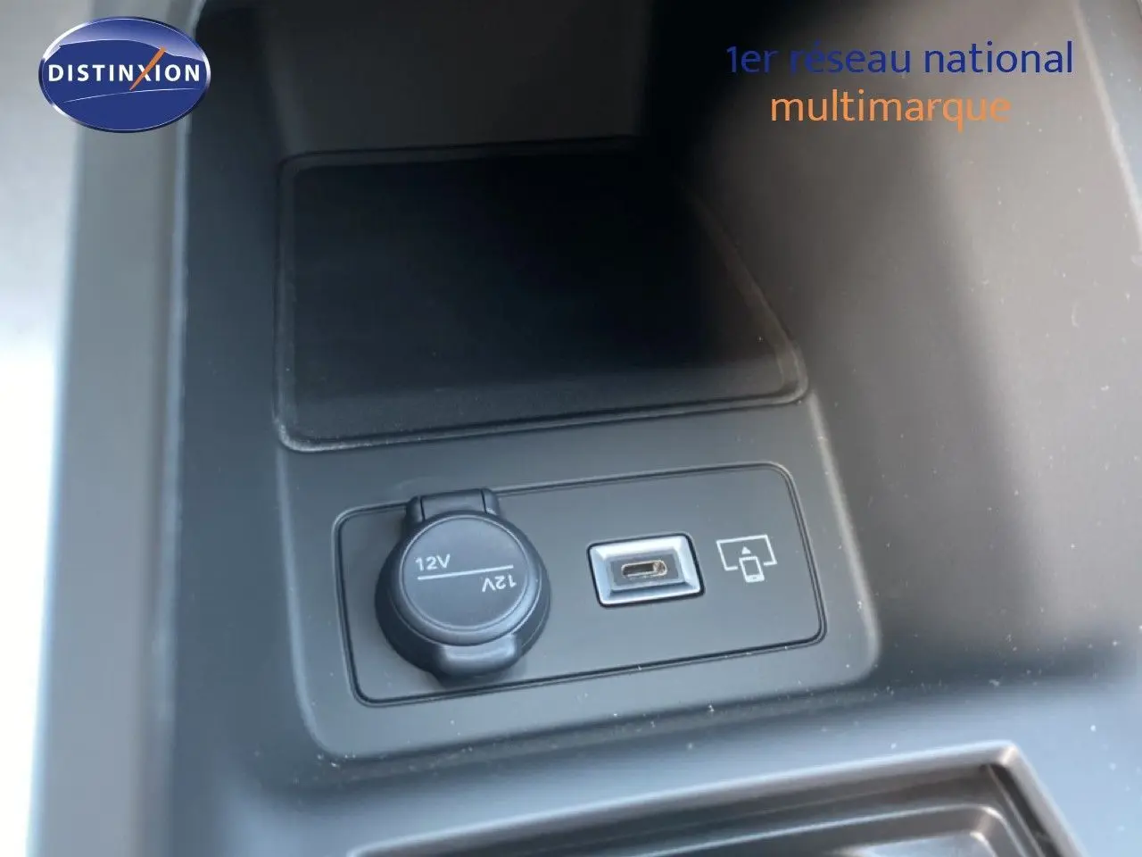 Prise 12V et port USB intégrés dans la console centrale d’une Peugeot 308 Hybrid blanche, vue en gros plan.
