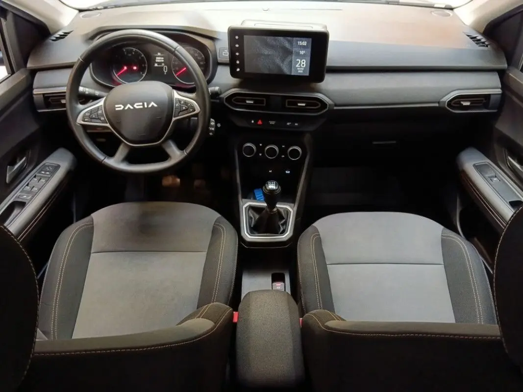 Vue intérieure avant de la Dacia Sandero Stepway 2025, tableau de bord avec écran tactile et volant multifonction noir.