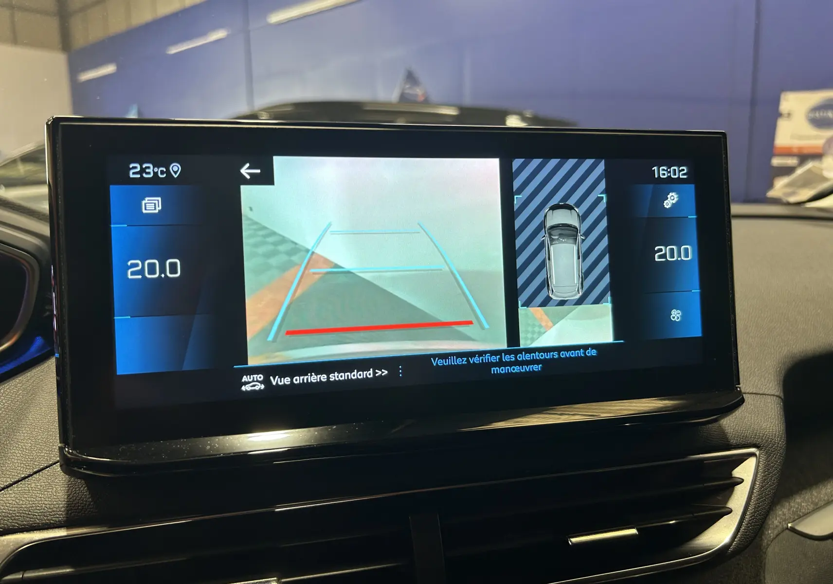 Écran tactile du tableau de bord du Peugeot 3008 gris Platinium montrant la caméra de recul et la température intérieure à 20°C.