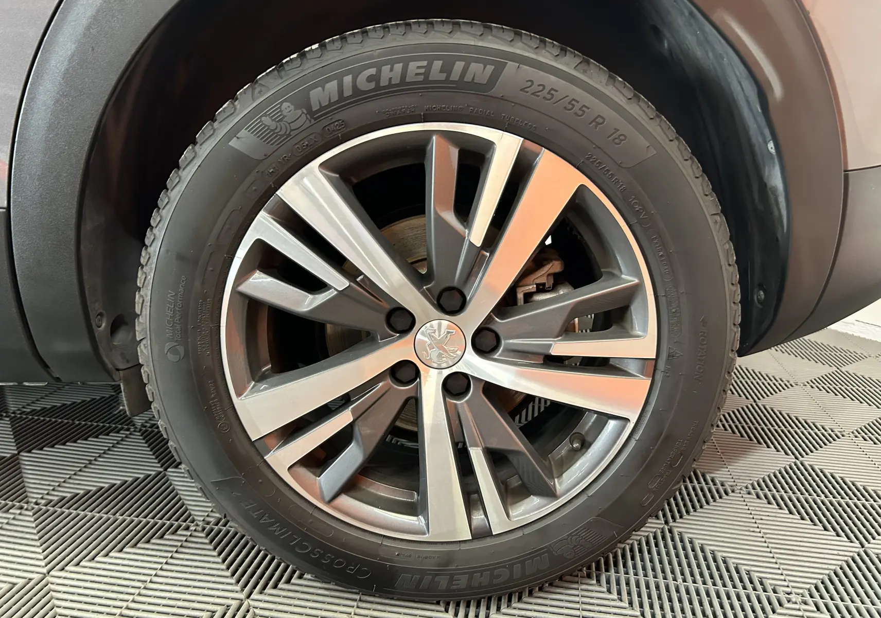 Gros plan sur la roue avant droite d’un Peugeot 3008 gris Platinium avec jante alliage et pneu Michelin.
