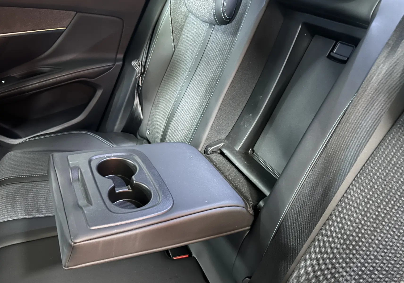 Vue intérieure du siège arrière droit de la Peugeot 3008 gris Platinium avec accoudoir central et porte-gobelets déployés.