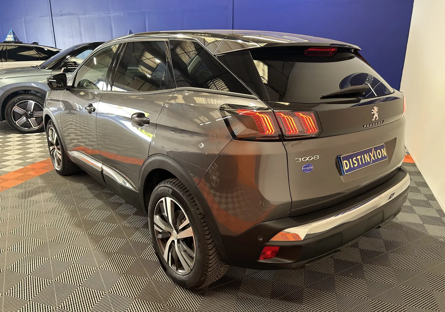 Vue 3/4 arrière droite d’un Peugeot 3008 gris Platinium avec feux arrière LED et jantes alliage en showroom.