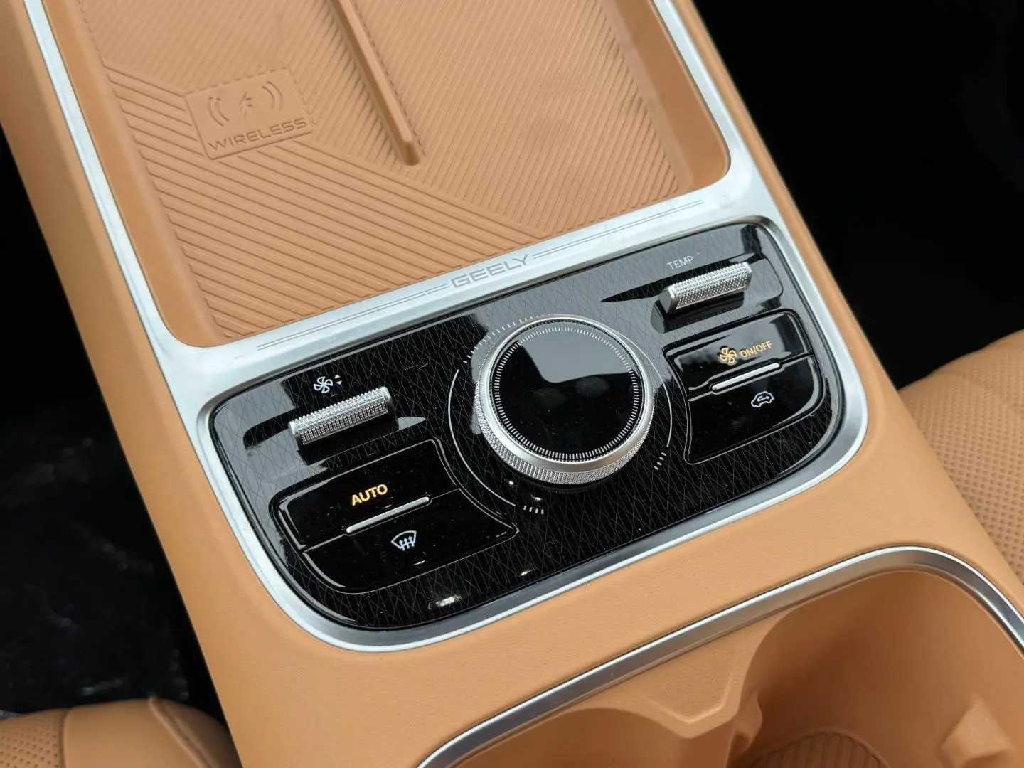 Gros plan sur la console centrale beige du Geely STARRAY 1.5 EM-i avec commandes clim et surface de charge sans fil.