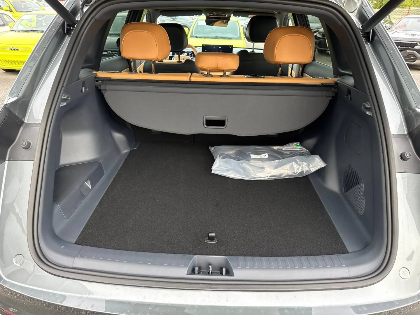 Coffre ouvert vu de l'arrière du Geely STARRAY gris Volcanic avec banquette arrière cuir marron et cache-bagages.