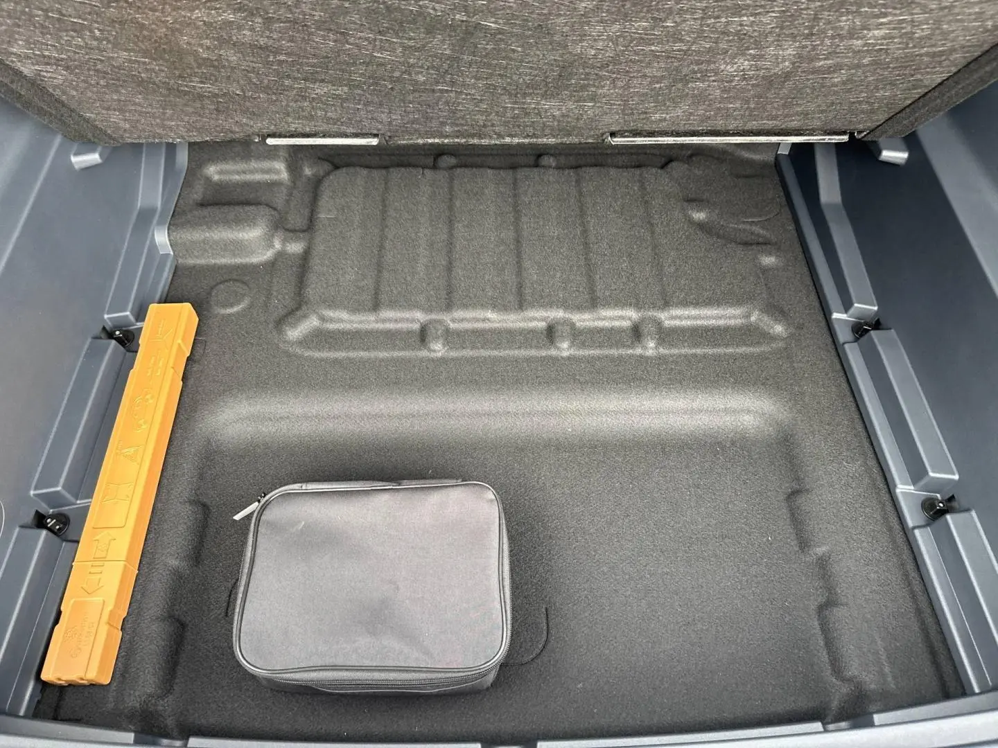 Vue plongeante sur le coffre vide du Geely STARRAY 1.5 EM-i 262ch Max+ en Volcanic Grey Metallic, avec trousse noire.