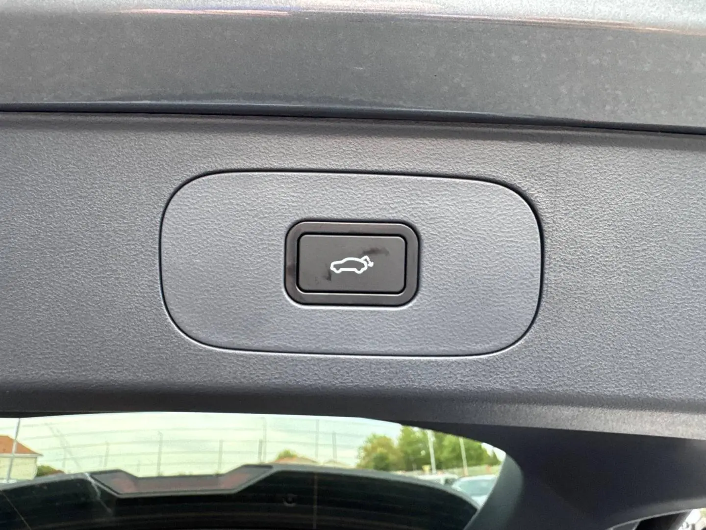 Bouton d'ouverture électrique du coffre sur la porte arrière du Geely STARRAY gris Volcanic, vue intérieure.