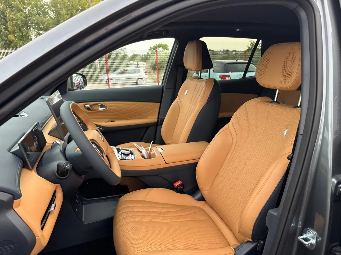 Vue intérieure côté conducteur du Geely STARRAY 1.5 EM-i 262ch Max+ avec sellerie cuir beige et tableau de bord Volcanic Grey Metallic.