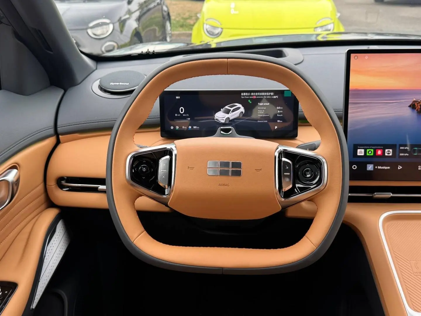 Vue intérieure centrée sur le volant carré cuir beige du Geely STARRAY avec tableau de bord numérique et écran tactile.