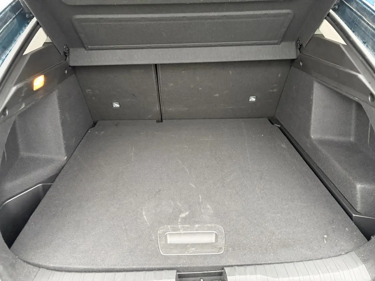 Coffre ouvert de la Renault Arkana bleu Zanzibar, montrant un plancher plat et un éclairage intérieur à gauche.