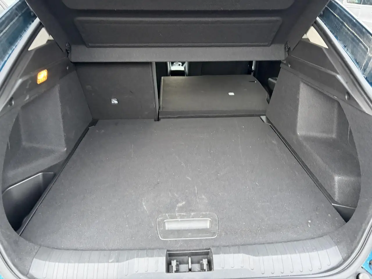 Coffre ouvert du Renault Arkana Bleu Zanzibar, vue de l’arrière avec banquette arrière partiellement rabattue.