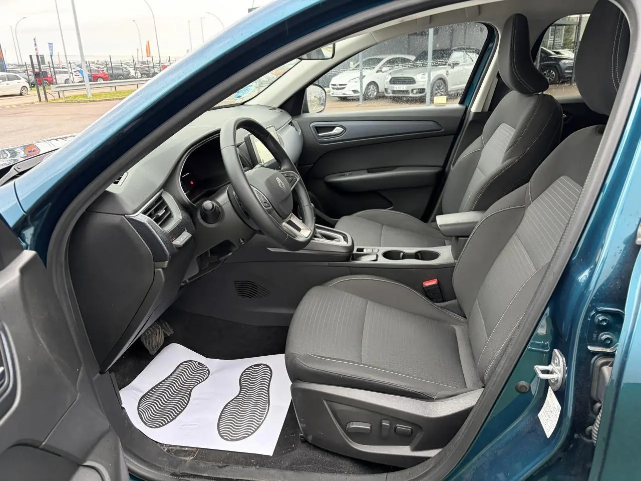 Vue intérieure côté conducteur de la Renault Arkana 2025 bleu Zanzibar, sièges gris et volant textile grainé.