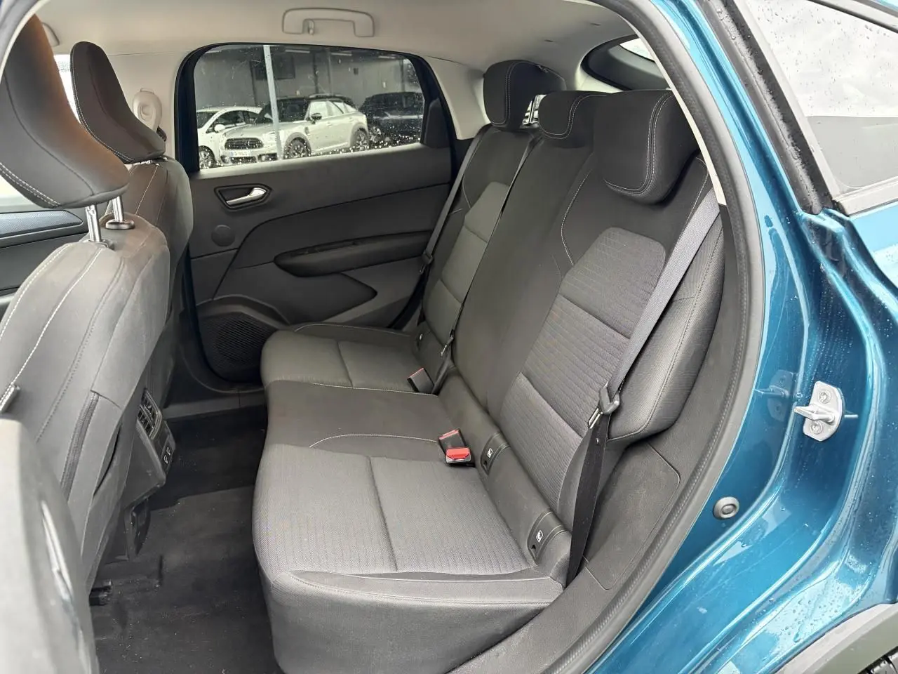 Vue intérieure arrière côté droit du Renault Arkana 2025 bleu Zanzibar, montrant la banquette noire et les portières.