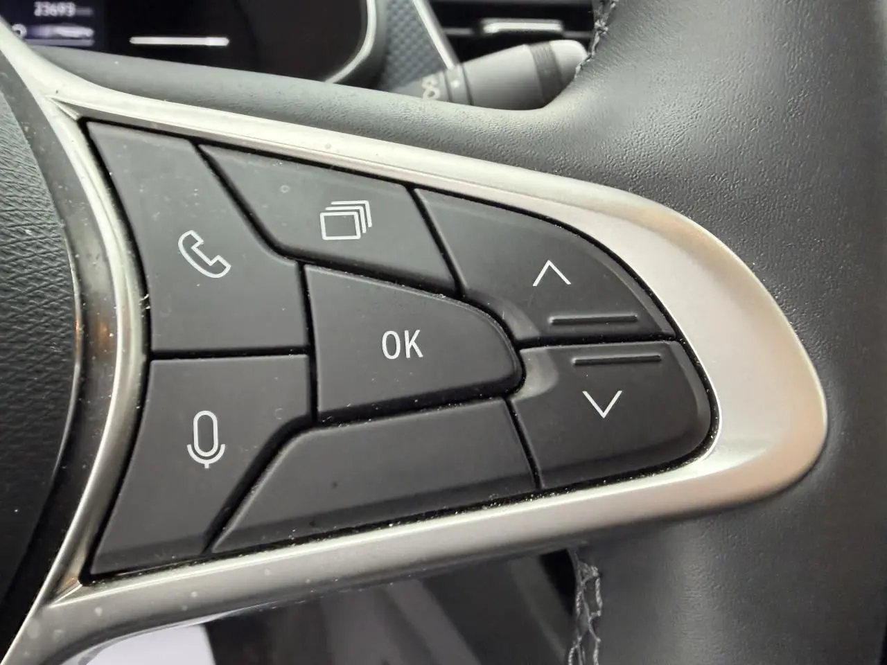 Gros plan sur les commandes au volant à droite du Renault Arkana 2025, boutons noirs avec cadre argenté.