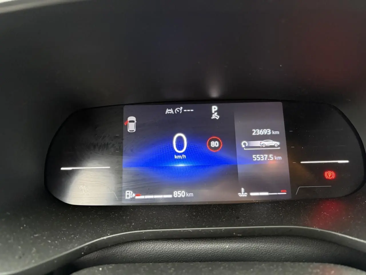 Tableau de bord numérique du Renault Arkana affichant vitesse, autonomie et alertes, vue frontale rapprochée.