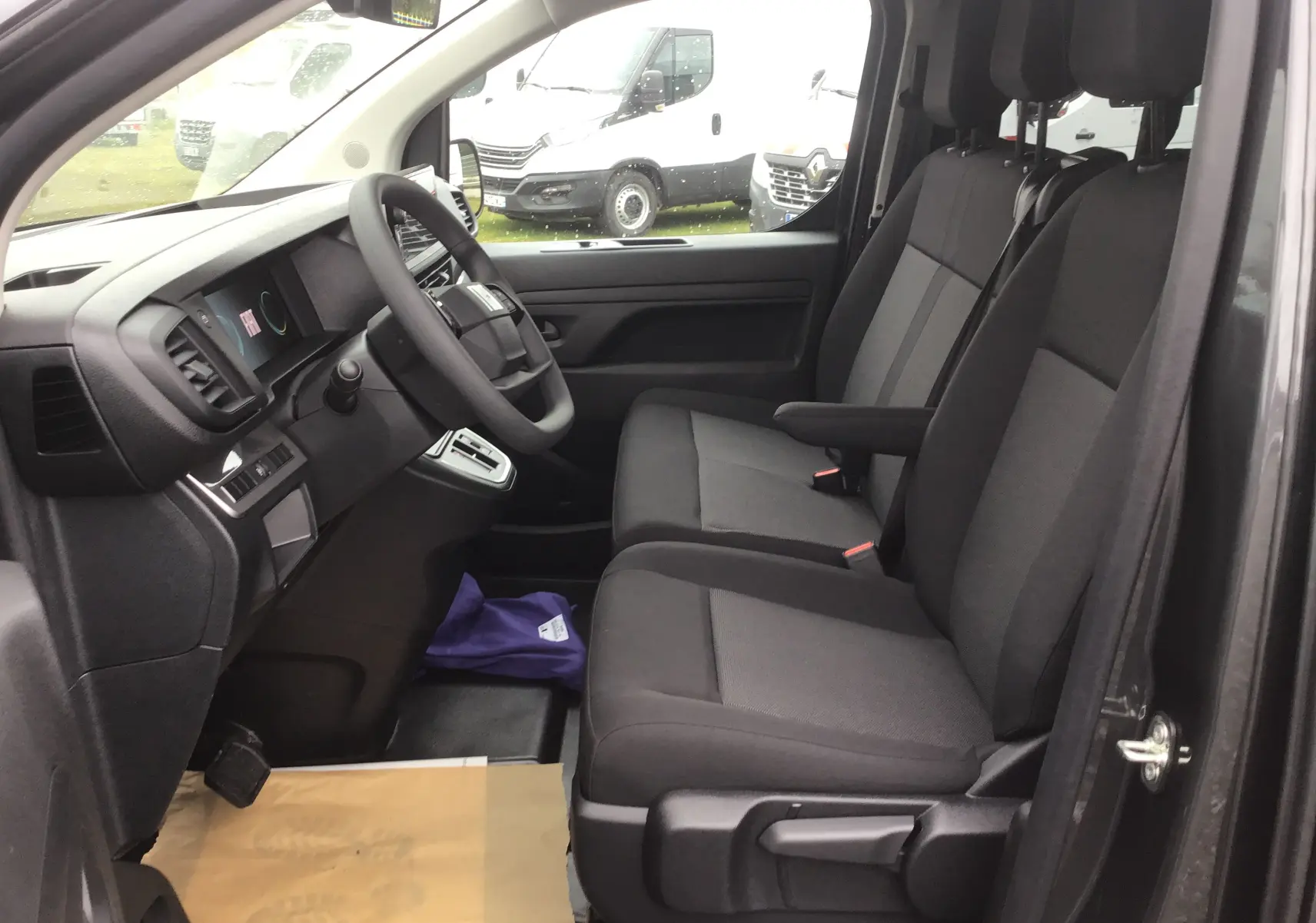 Vue intérieure côté conducteur du Fiat Scudo Combi gris titane, montrant les sièges avant et le tableau de bord moderne.