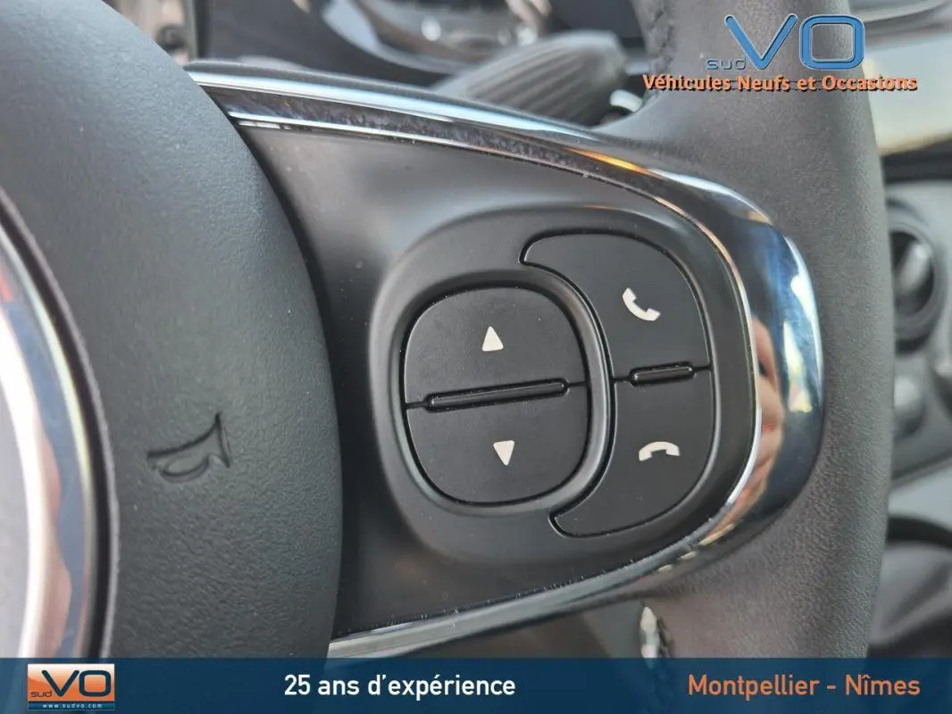 Gros plan sur les commandes de téléphone et volume au volant d'une FIAT 500C noire 2024, intérieur visible.