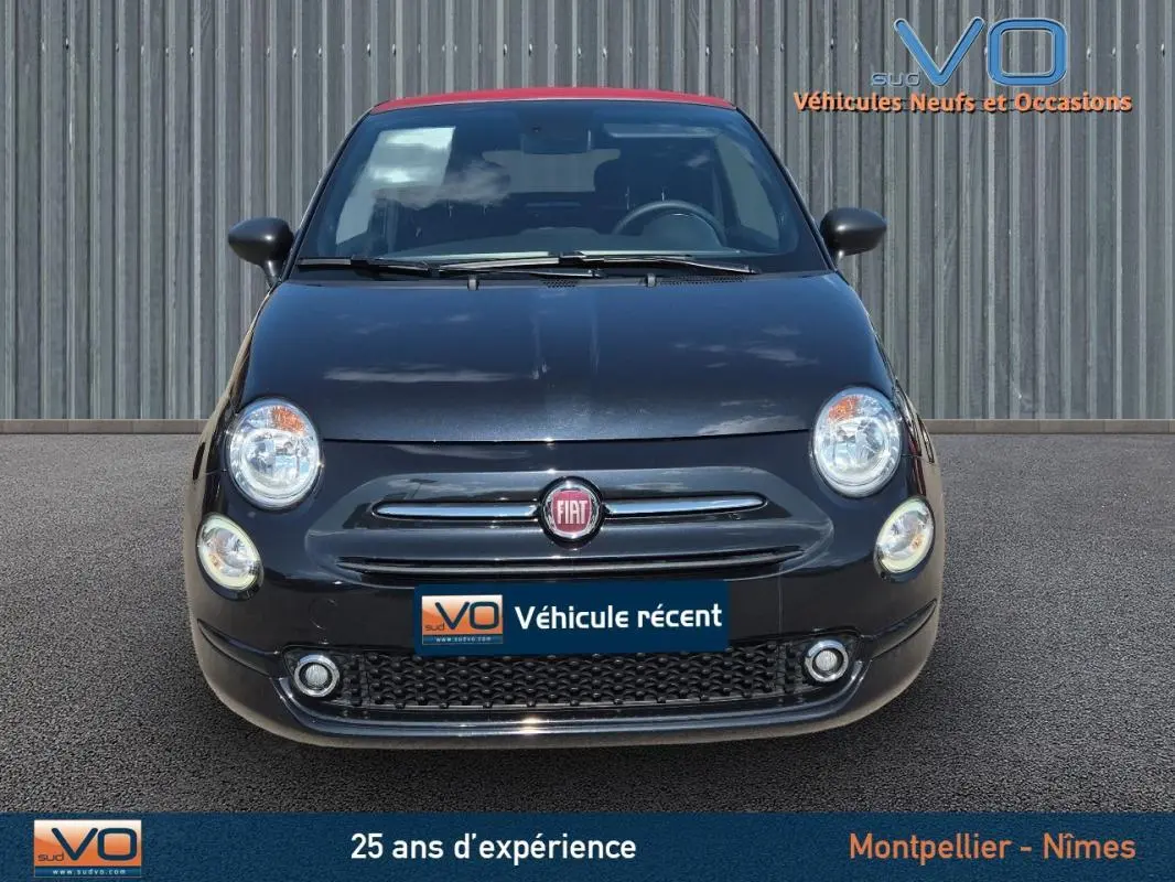 Vue frontale d'une FIAT 500C noire avec toit rouge, jantes alliage et logo FIAT bien visible.