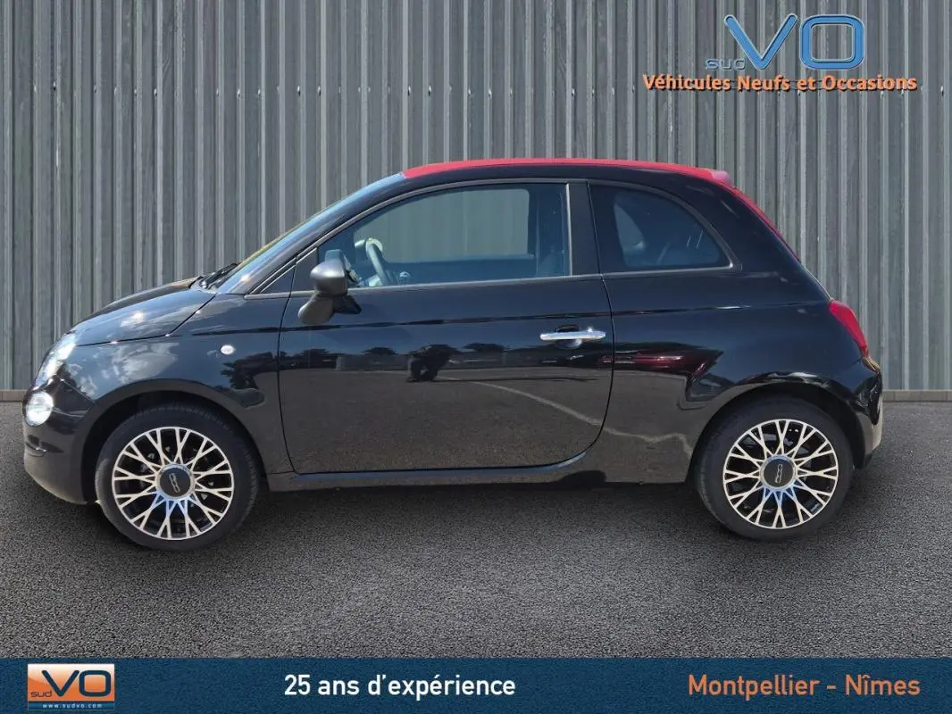 Profil côté gauche d'une FIAT 500C noire 2024 avec jantes alliage 15 pouces, toit rouge et finition pack confort.