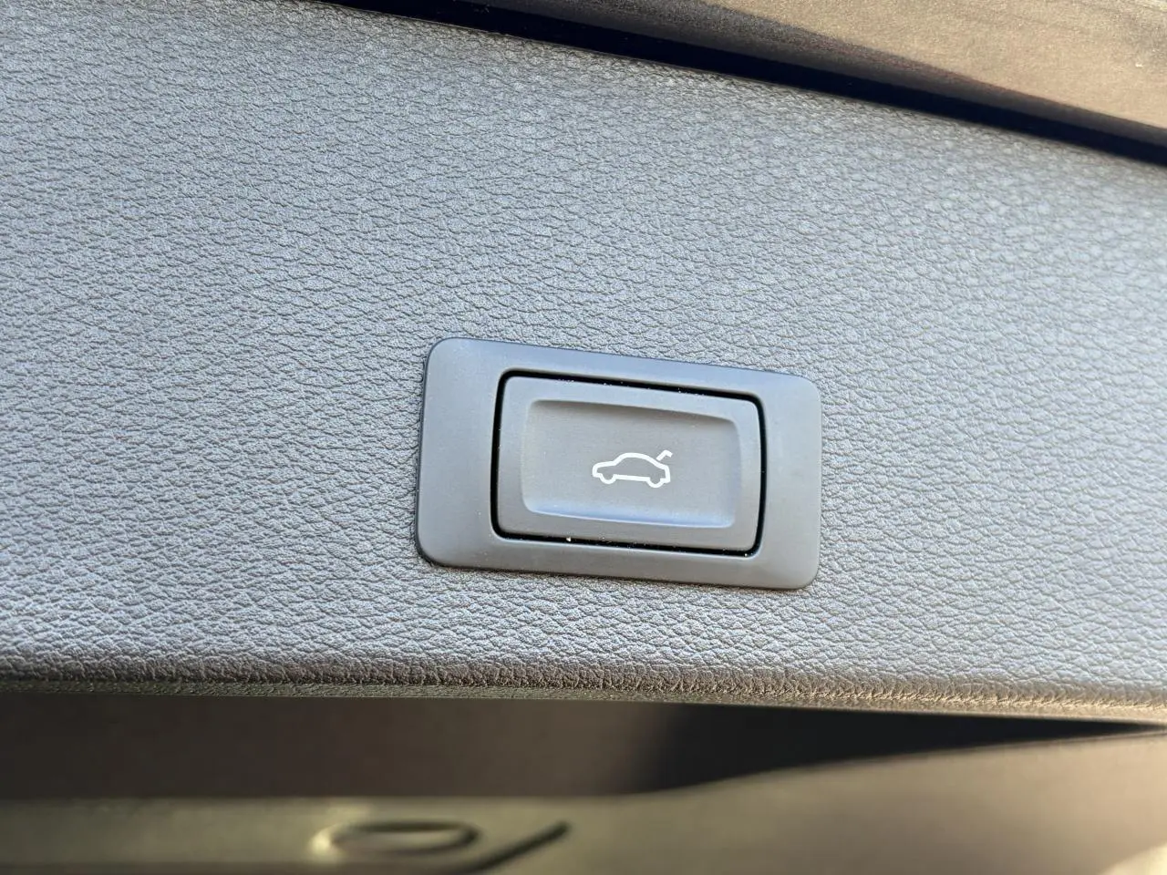 Bouton de commande du hayon électrique sur la garniture intérieure d’un Audi Q2 Gris Daytona, vue rapprochée.