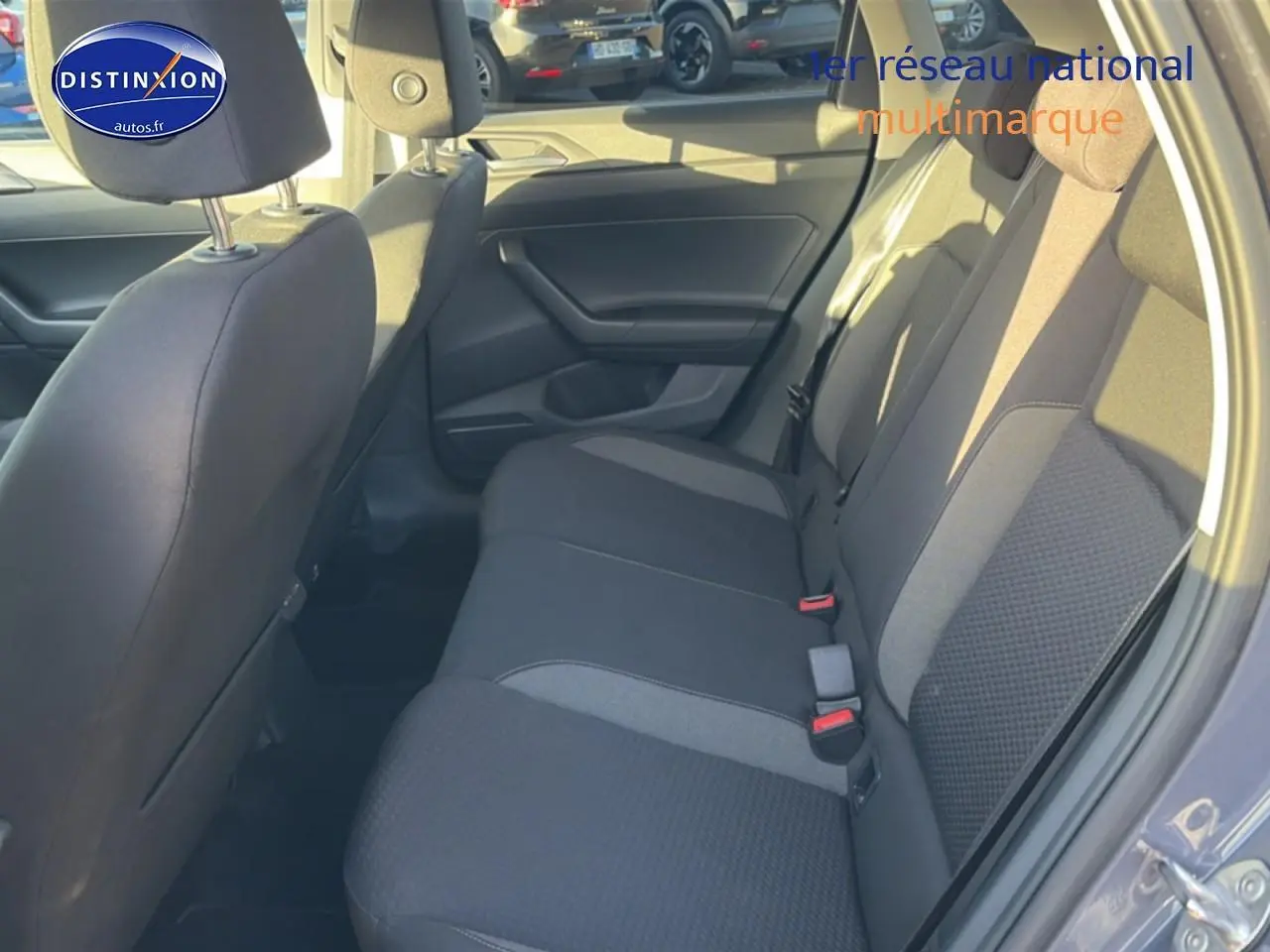 Vue intérieure côté droit sur la banquette arrière grise du Volkswagen Polo 2025 avec habillage tissu et ceintures rouges.