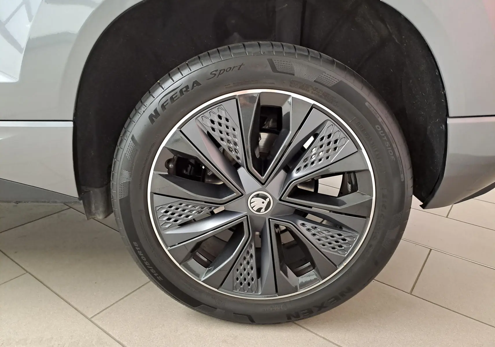 Gros plan sur la roue avant gauche du Skoda Karoq gris graphite, mettant en valeur la jante au design moderne et sportif.