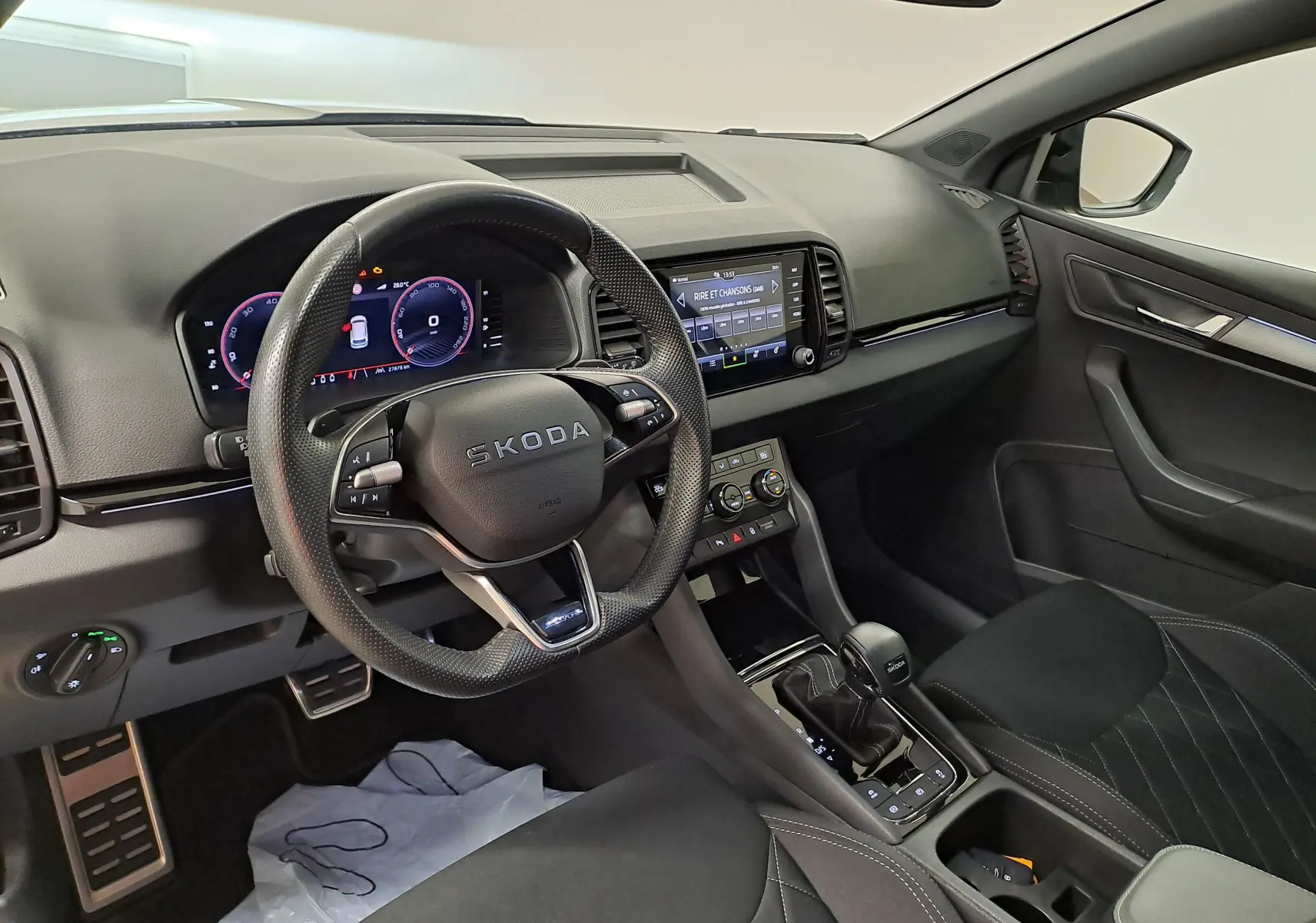 Vue intérieure côté conducteur du tableau de bord et volant SKODA KAROQ 2.0 TDI 150 DSG7 avec écran tactile et commandes au volant.