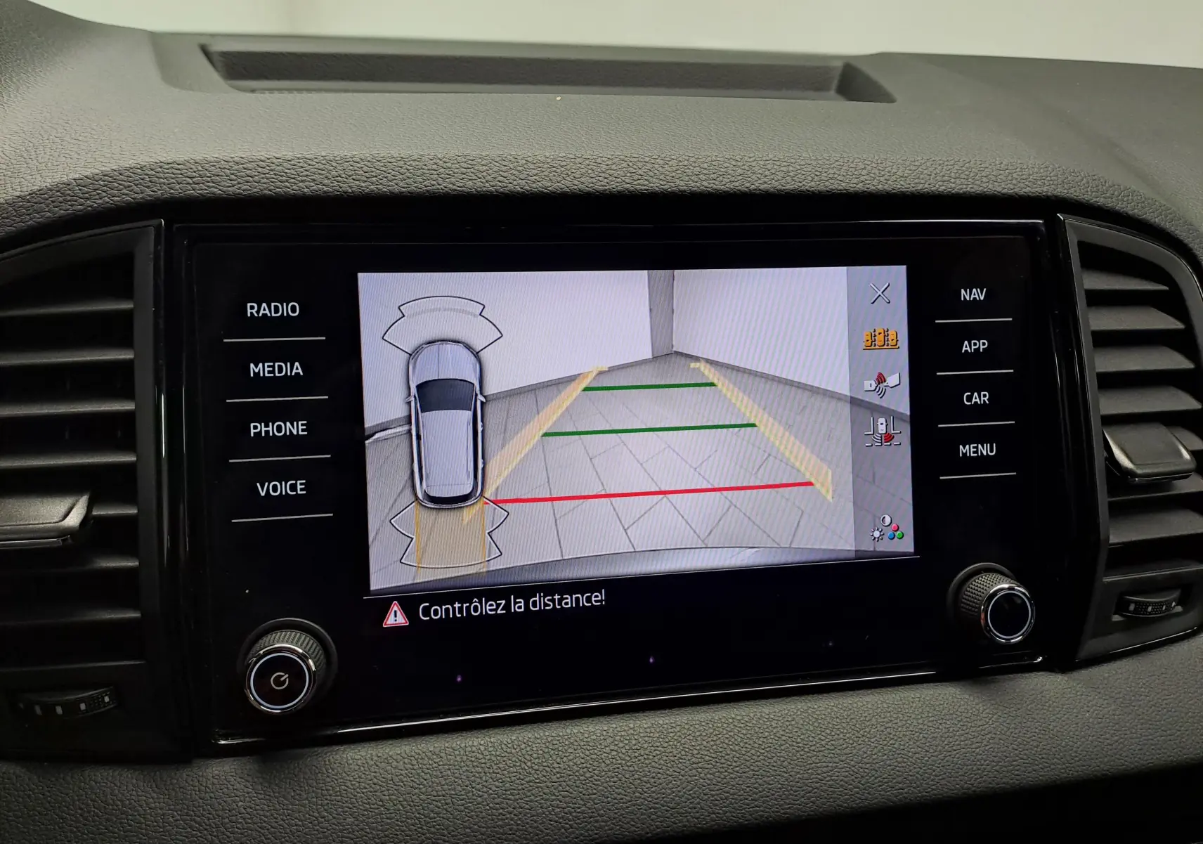 Écran central du Skoda Karoq 2025 montrant la caméra de recul avec lignes de guidage et alertes de distance.