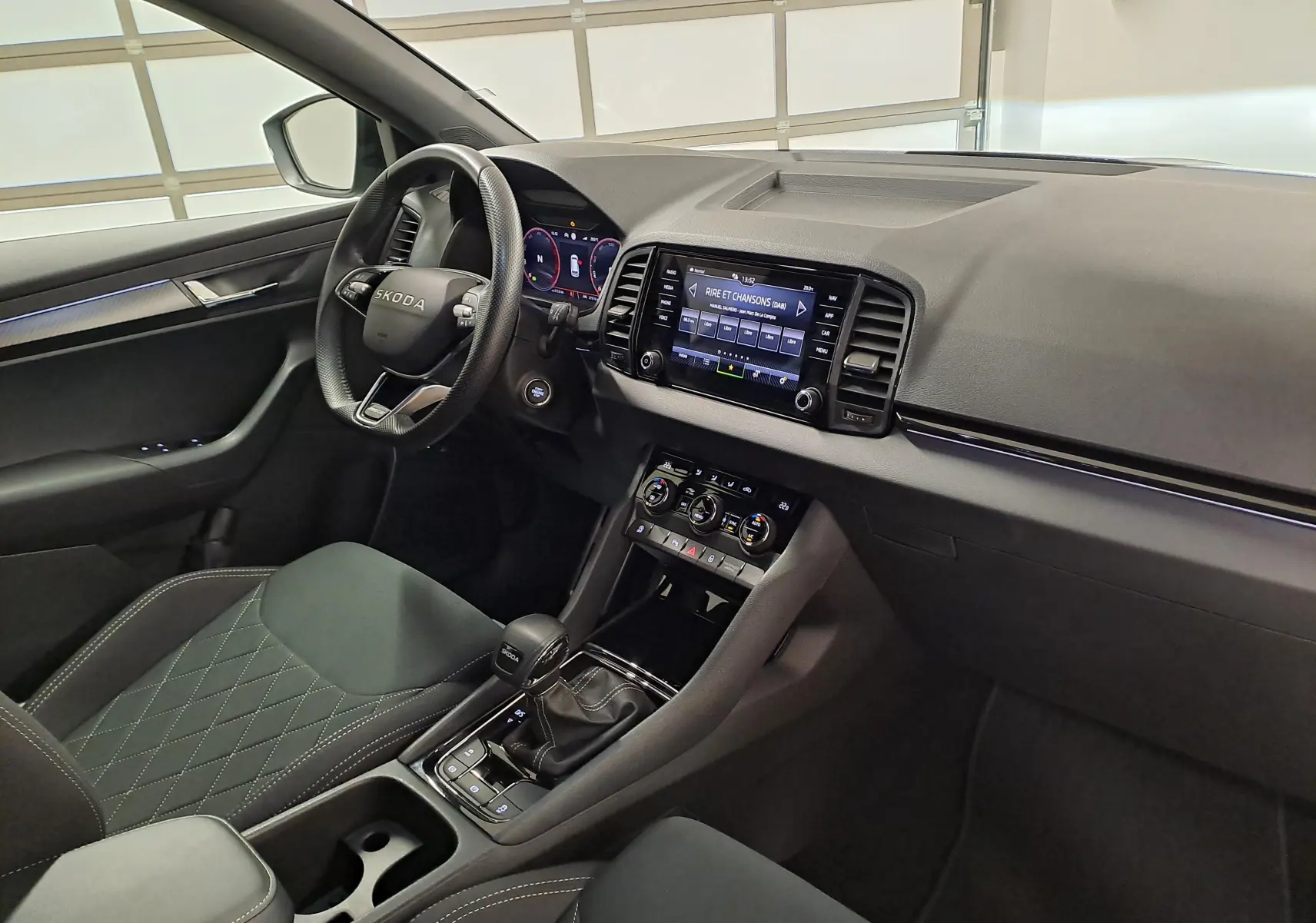 Vue intérieure côté conducteur du Skoda Karoq 2025, tableau de bord moderne avec écran tactile et volant multifonction.