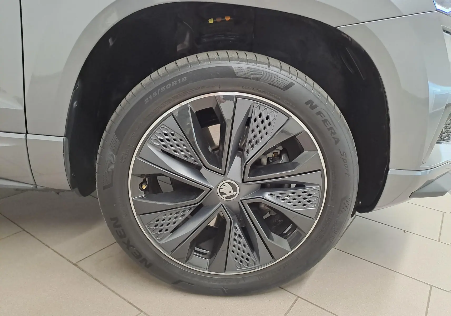 Gros plan sur la roue avant droite du Skoda Karoq gris graphite, mettant en valeur la jante noire au design moderne.