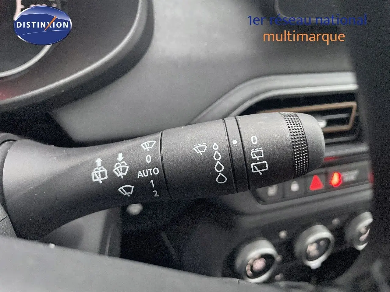 Gros plan sur la commande d’essuie-glace à gauche du volant dans l’habitacle sombre du Dacia Jogger gris schiste.