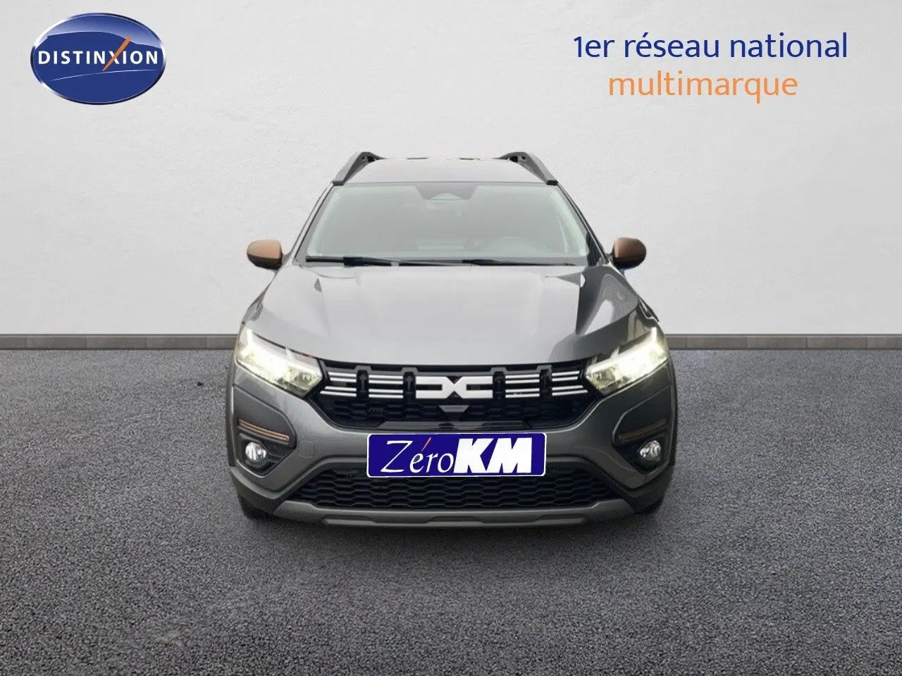 Vue avant d'un Dacia Jogger gris schiste métal avec calandre noire et feux allumés sur fond neutre.