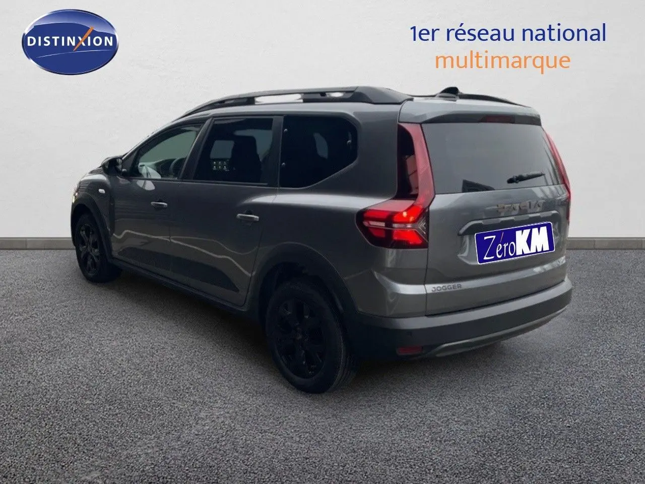 Vue 3/4 arrière droit d'un Dacia Jogger gris schiste métal avec feux arrière allumés et jantes noires.