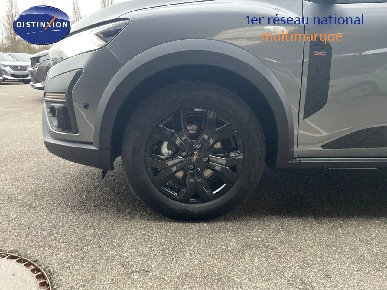 Gros plan sur la roue avant droite d’un Dacia Jogger gris schiste métal avec jante noire et badge Xtreme sur la porte.