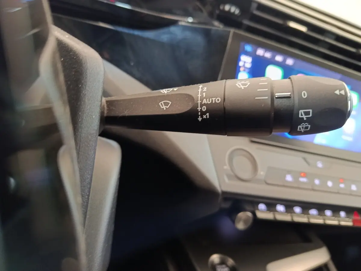 Gros plan sur la commande d’essuie-glace à gauche du volant dans l’habitacle sombre de la Peugeot 308 2023.