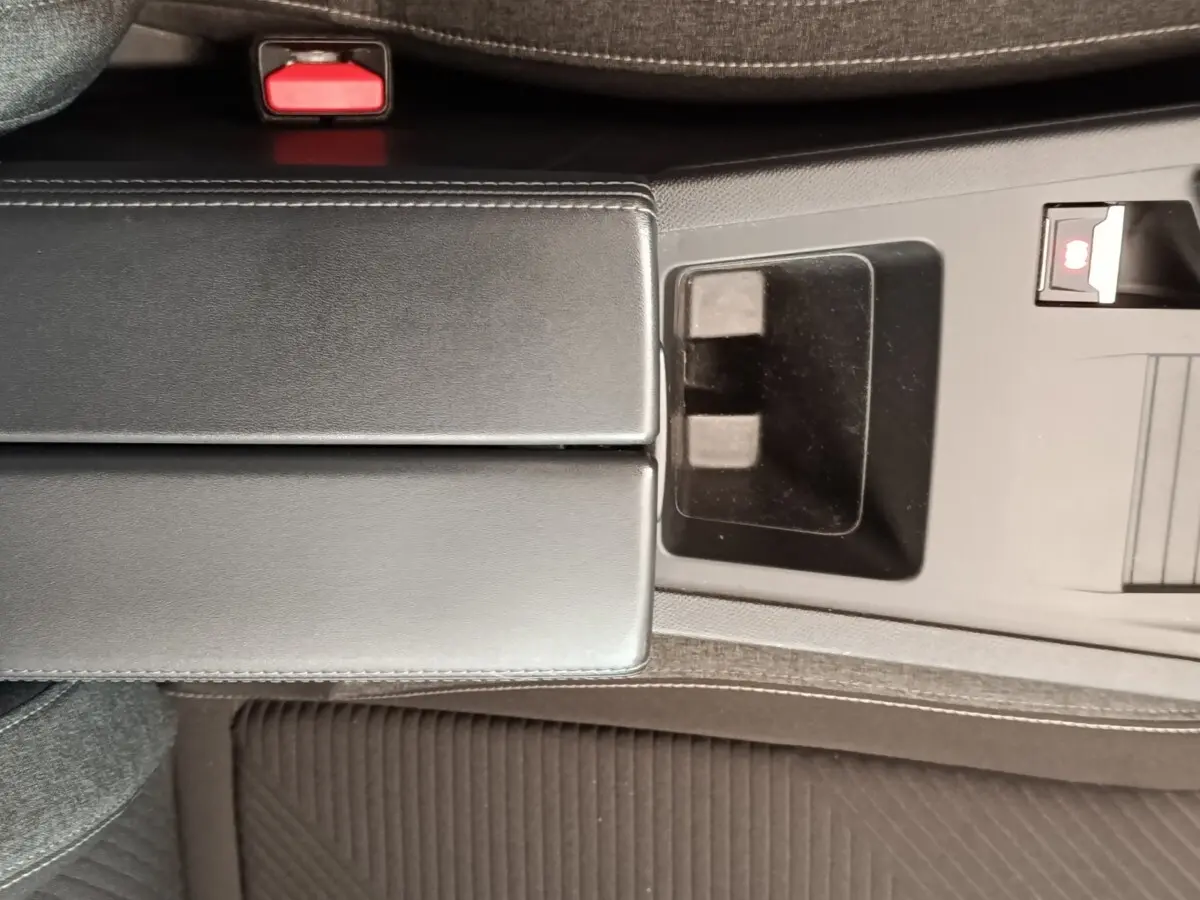 Vue rapprochée de la console centrale noire de la Peugeot 308 2023 avec accoudoir et frein à main électrique.