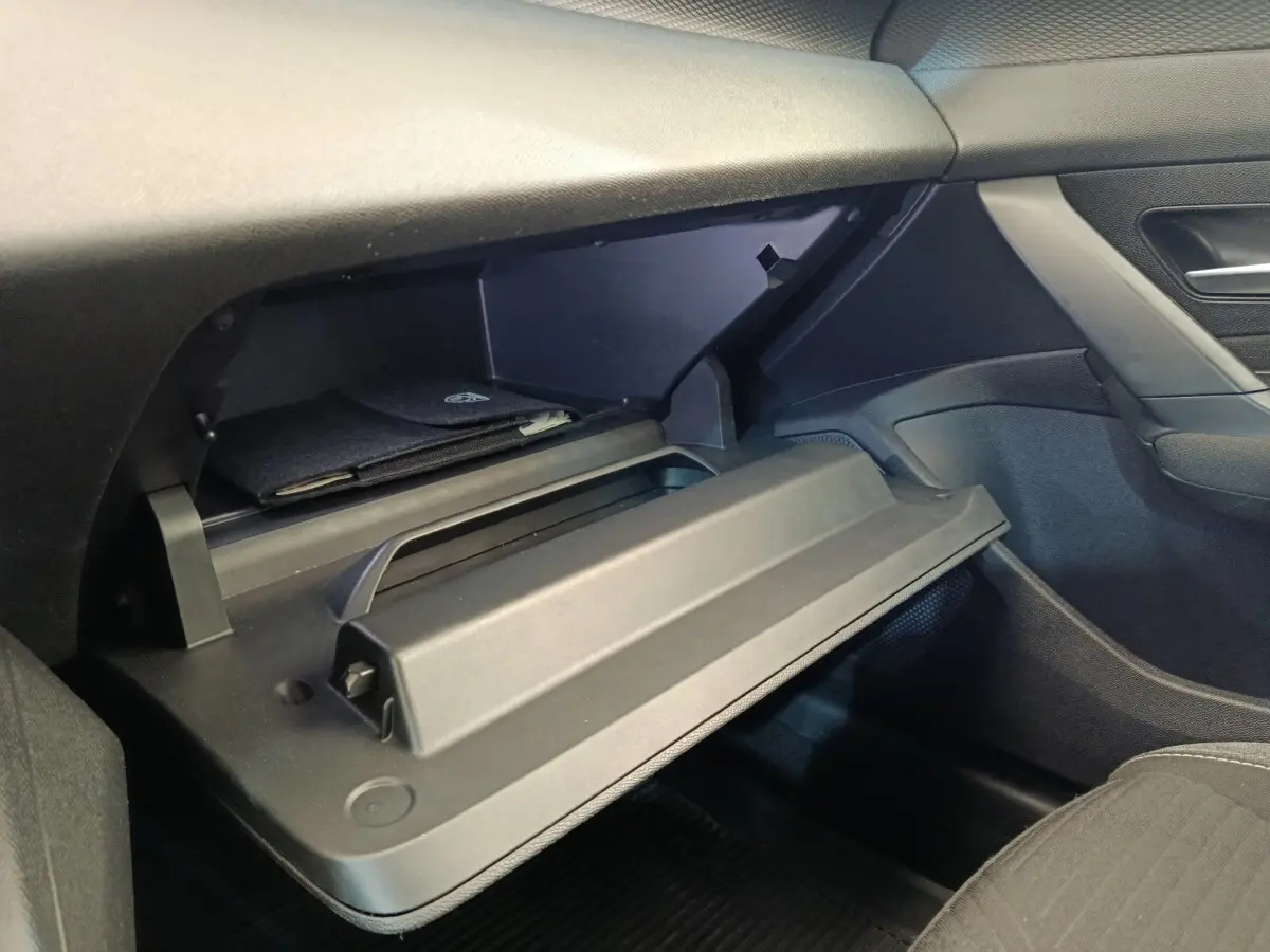 Vue intérieure côté passager de la Peugeot 308 2023 essence, boîte auto, avec boîte à gants ouverte et rangement noir.