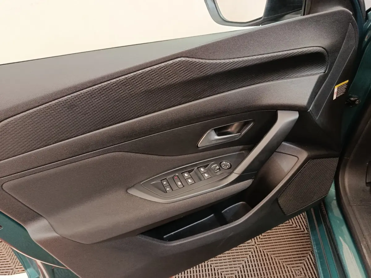 Vue rapprochée de la porte avant gauche noire de la Peugeot 308 2023, avec commandes de vitres et haut-parleur intégré.
