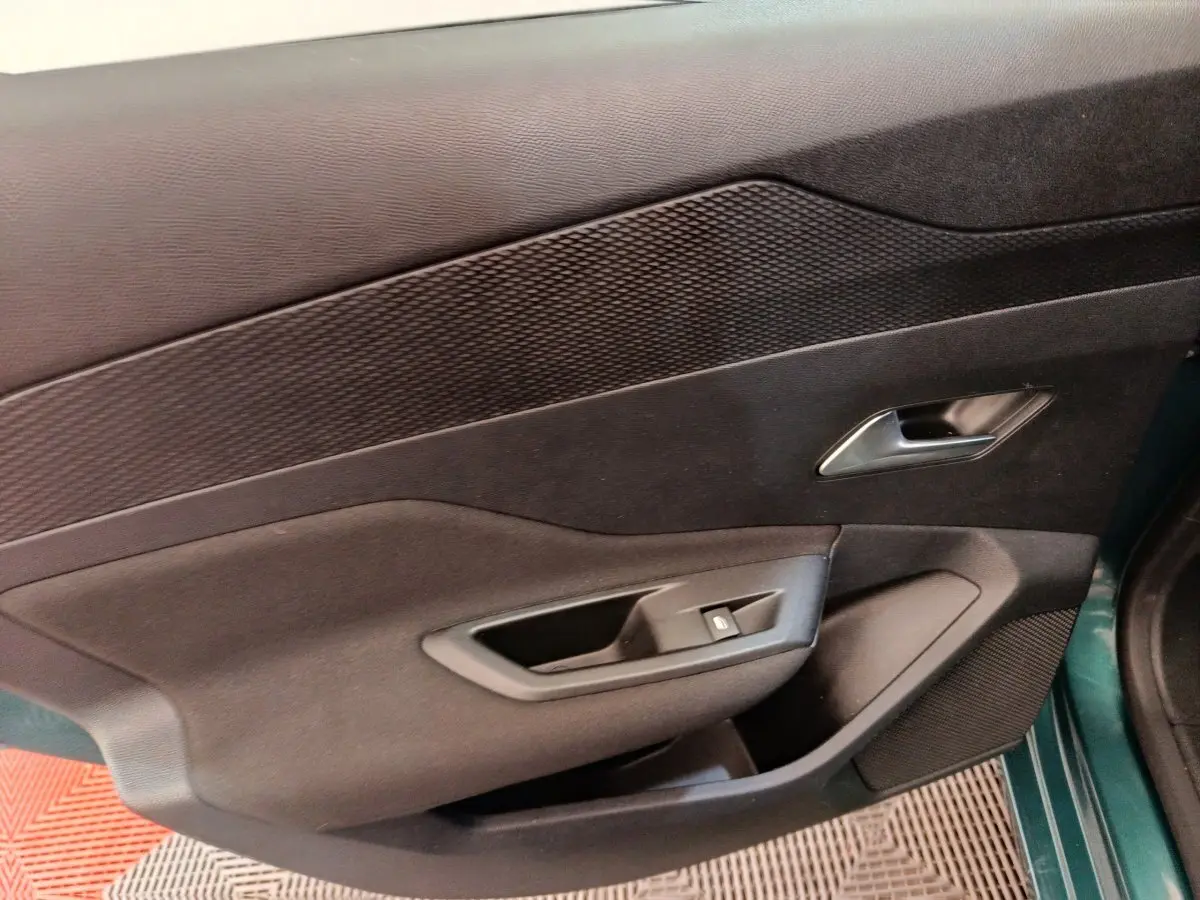 Vue intérieure sur la porte avant gauche noire avec poignée argentée et commande de fenêtre d’une Peugeot 308 2023.