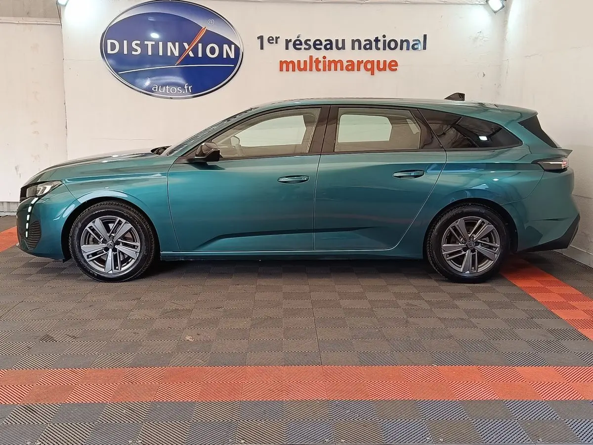 Peugeot 308 break 2023 vert bleu en profil droit, avec jantes alliage et feux arrière LED distinctifs.