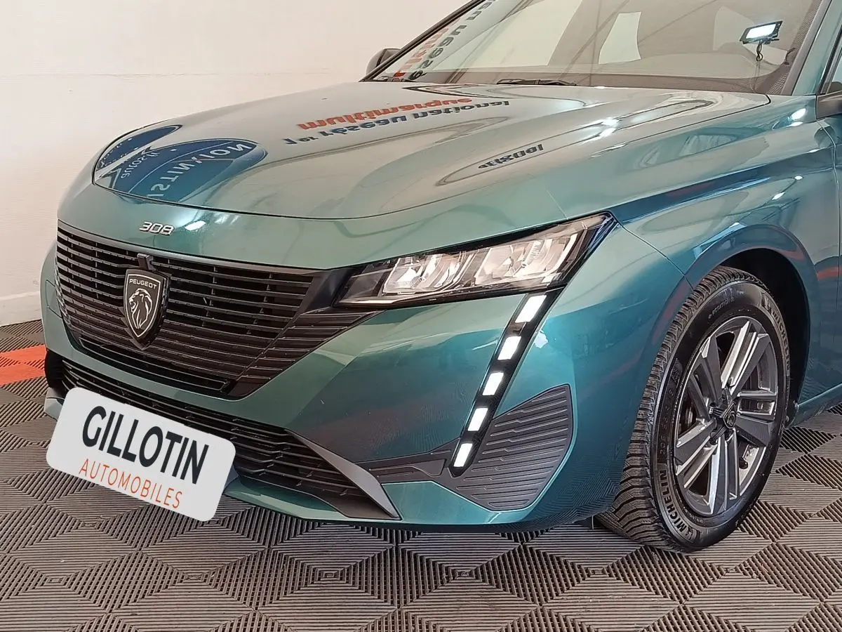 Vue 3/4 avant droit d'une Peugeot 308 2023 vert métallisé avec signature lumineuse LED verticale et calandre noire.
