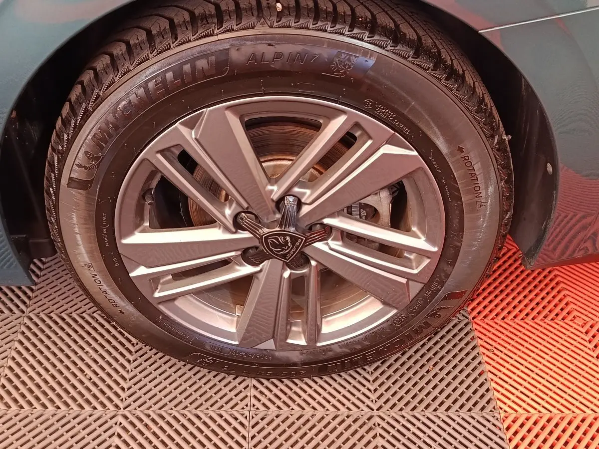 Gros plan sur la roue avant droite d'une Peugeot 308 2023, jante alliage grise et pneu Michelin Alpine.