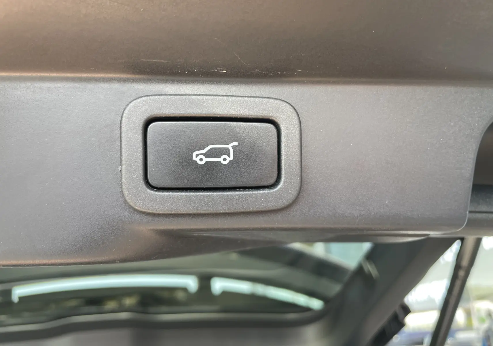 Bouton d'ouverture électrique du hayon sur le coffre d'un Range Rover Sport gris Eiger Grey, vue intérieure.
