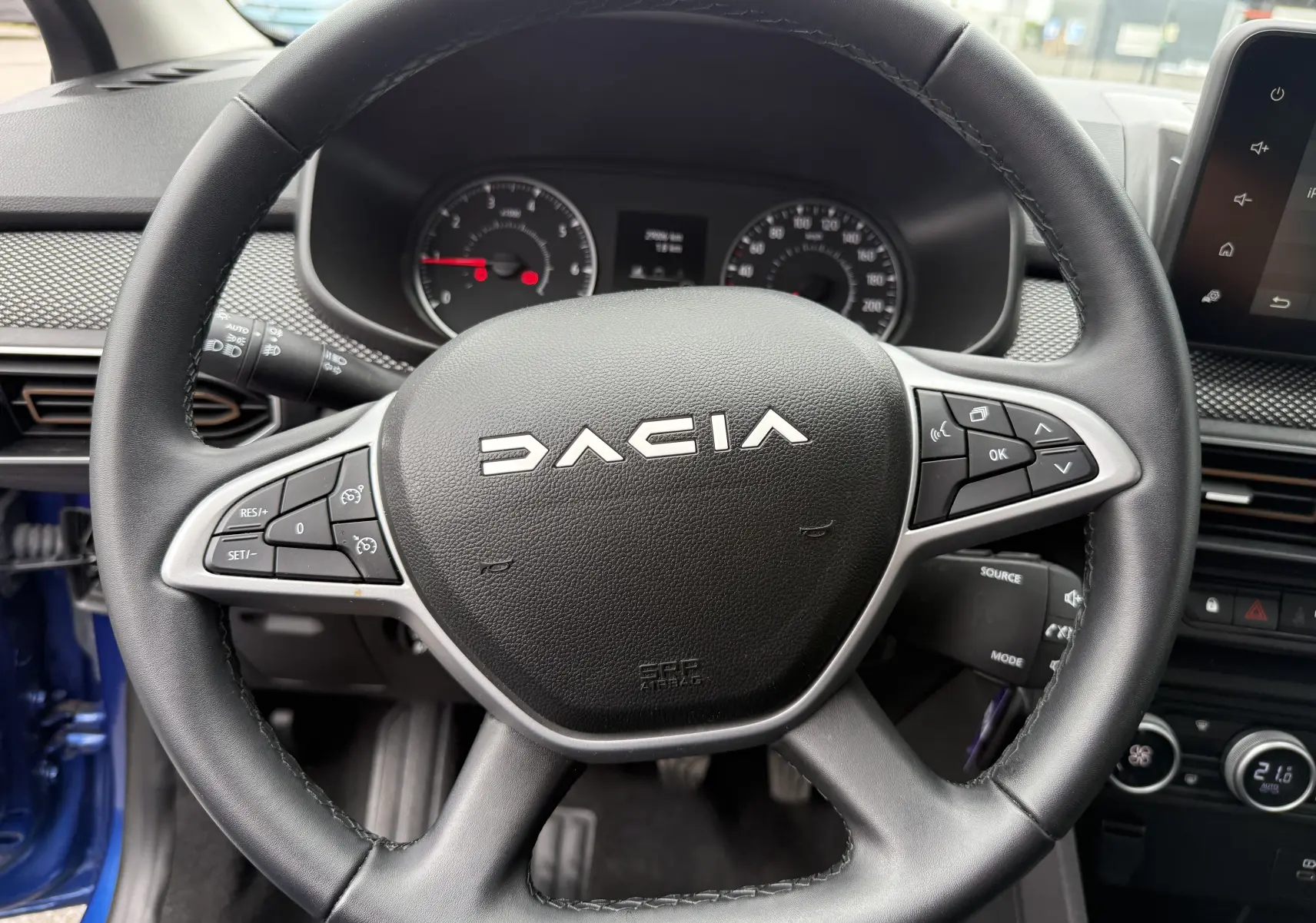 Vue rapprochée du volant noir de la Dacia Sandero Stepway 2025 avec commandes intégrées et tableau de bord en arrière-plan.