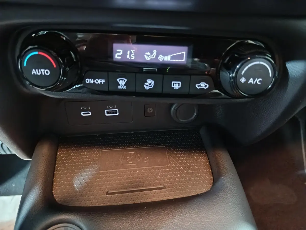 Détail de la console centrale du Nissan Juke 2025, montrant les commandes de climatisation et la zone de recharge sans fil.