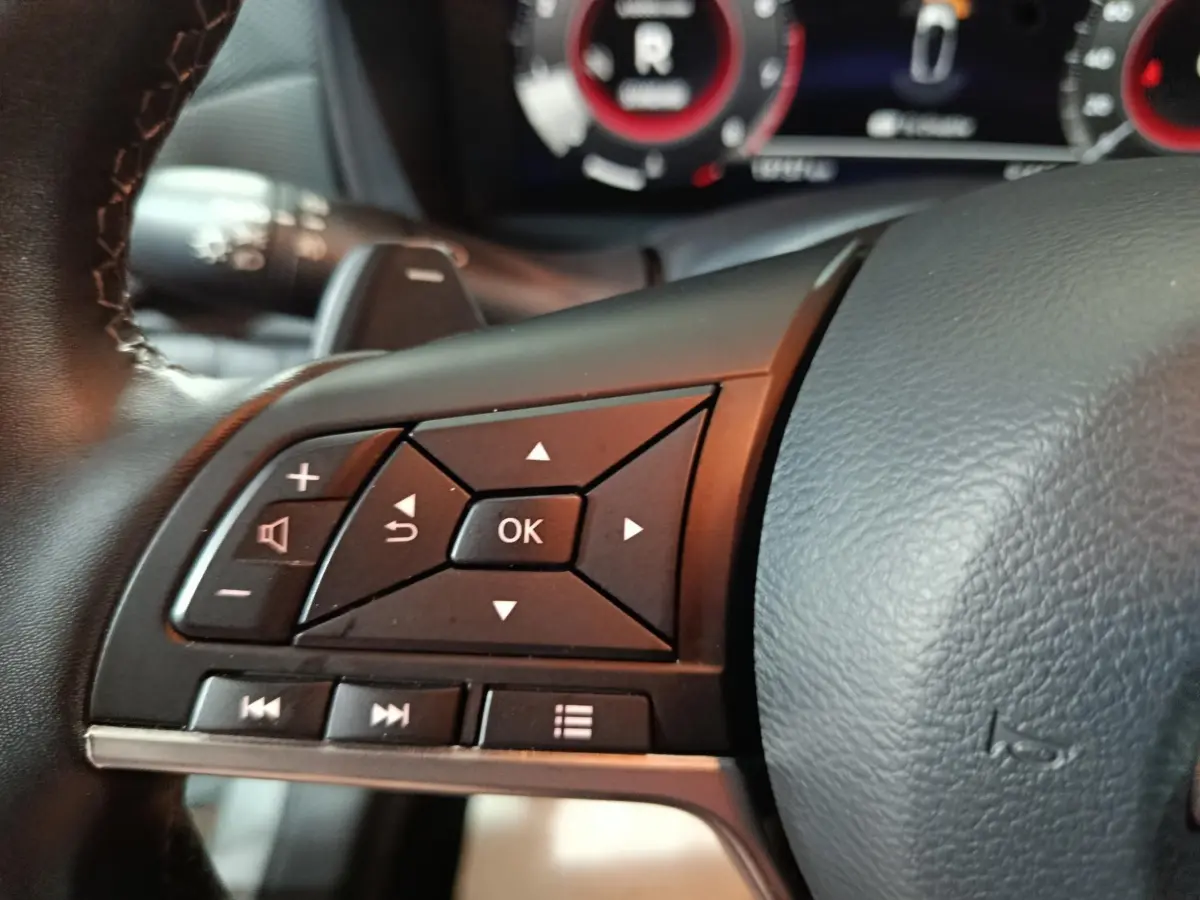 Gros plan sur les commandes multifonctions noires à gauche du volant cuir d'un Nissan Juke gris foncé 2025.