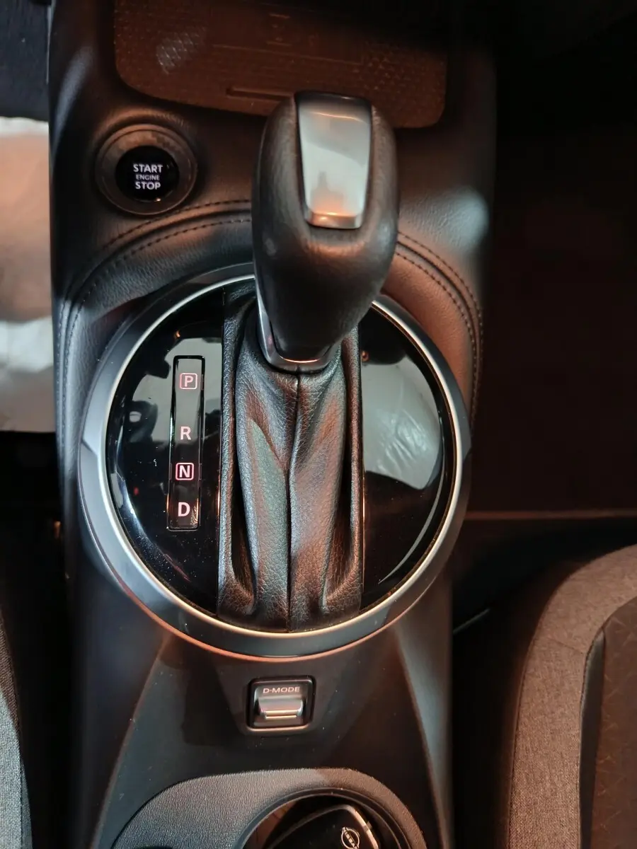 Gros plan sur la console centrale du Nissan Juke gris foncé 2025, avec levier de vitesse automatique et bouton démarrage.